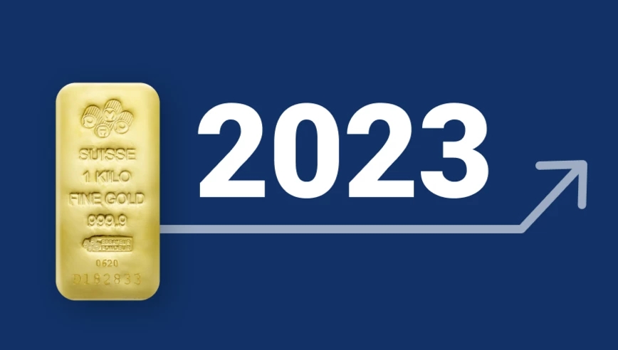 Un lingotto d’oro PAMP Suisse con la data 2023 e una freccia bianca su sfondo blu scuro.