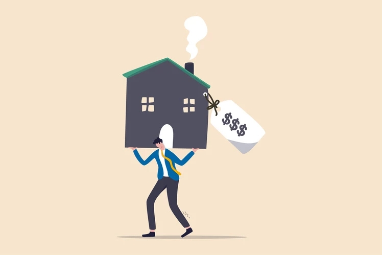 Ein Mann, der ein Haus mit einem teuren Preisschild auf den Schultern trägt, das für die hohen Kosten einer Immobilieninvestition steht