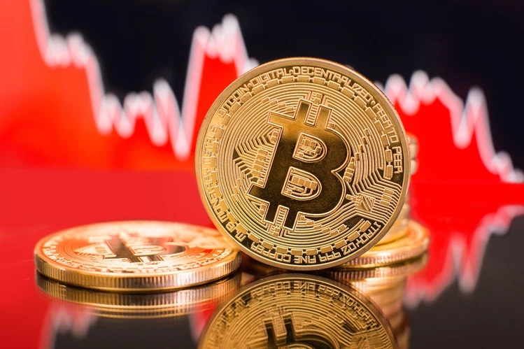 Gold-Bitcoin-Münzen mit fallenden und roten Aktienindikatoren im Hintergrund