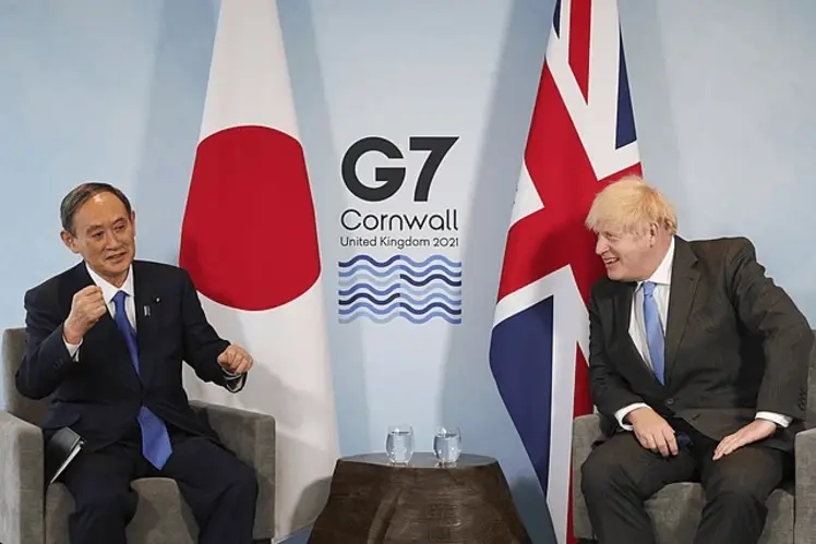 UK Prime Minister Boris Johnson and Japanese Prime Minister Yoshihide Suga attending a meeting on the sidelines of the G7 summit in Cornwall with the Japanese and British flags standing in the background. 