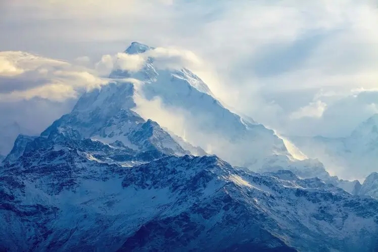 un'immagine che mostra montagne blu circondate da nebbia e nuvole