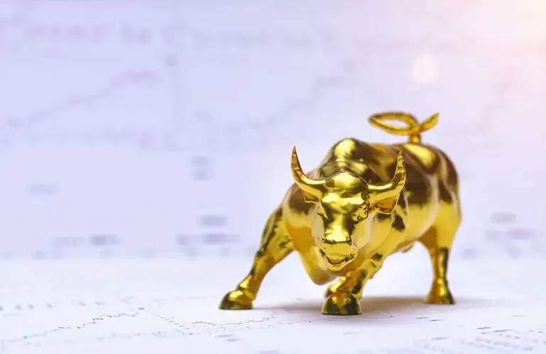 un toro d’oro con grafici azionari sullo sfondo a simboleggiare una crescente tendenza al rialzo dell’oro