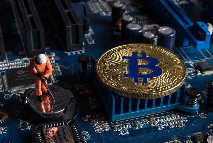 Un mineur de bitcoin extrait une pièce d'or physique pour représenter la monnaie numérique.
