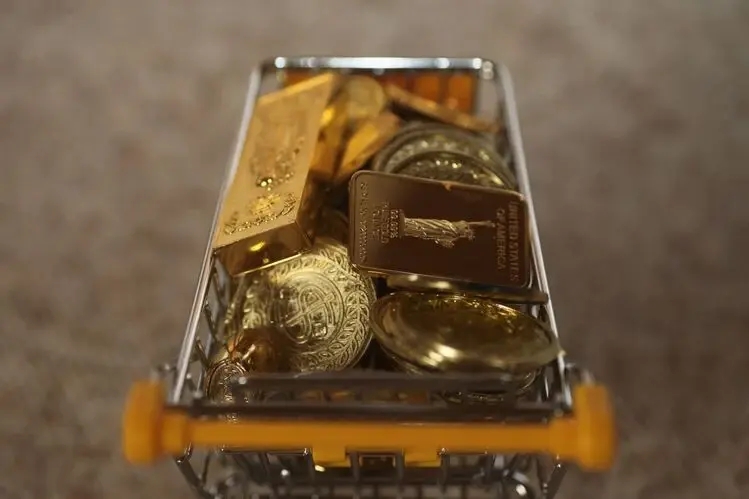 physical gold coins and gold bars filling a shopping cart to represent investors buying gold