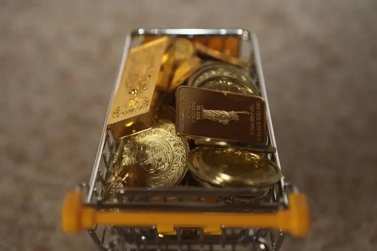 physical gold coins and gold bars filling a shopping cart to represent investors buying gold