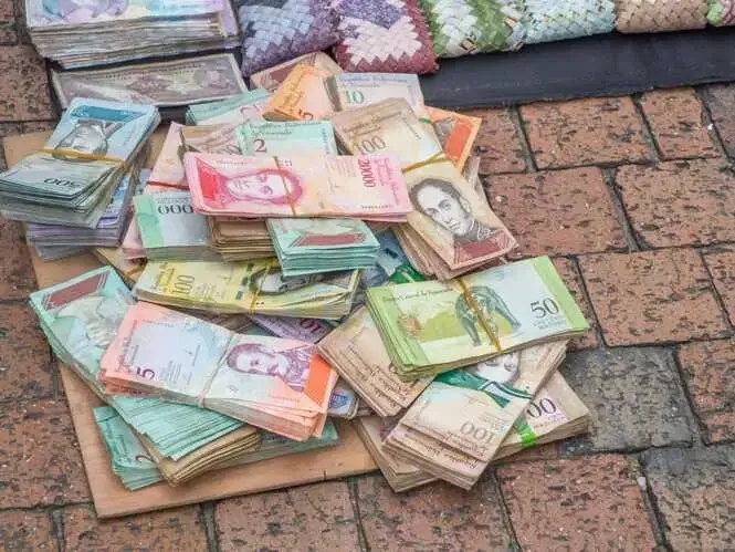 Il bolivar venezuelano abbandonato sul marciapiede vicino a borsette realizzate con la valuta nazionale