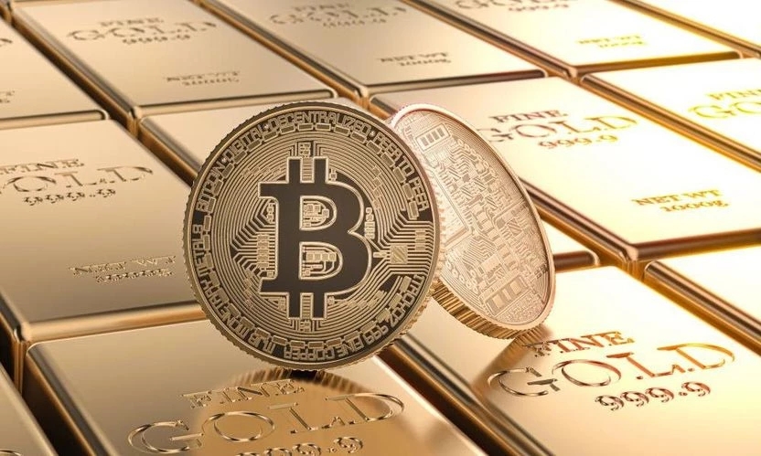 une fausse pièce d’un bitcoin en or posée sur des lingots d'or physique