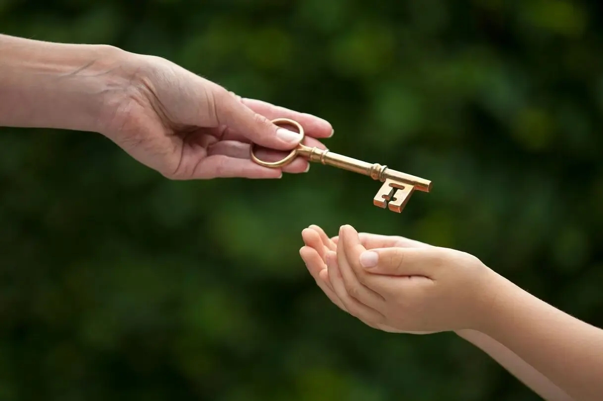 Eltern, die so früh wie möglich mit dem Sparen für die Zukunft ihrer Kinder beginnen, um ihnen ein verlässliches Sicherheitsnetz zu schaffen, dargestellt mit einem Bild, auf dem ein Erwachsener einem Kind einen goldenen Schlüssel übergibt