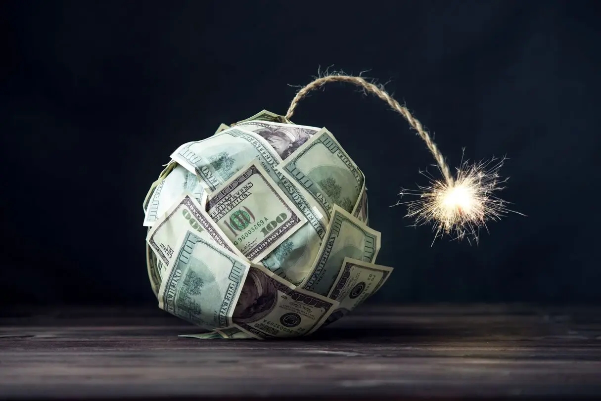 Une bombe représentant l'inflation, constituée de billets de 100 dollars US, en train de fumer et sur le point d'exploser sur l'économie mondiale.