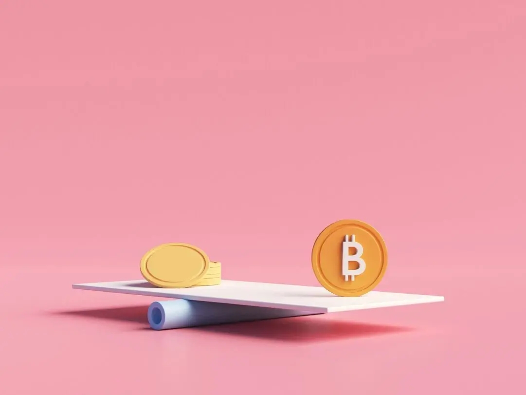 Plastic yellow gold coin and orange bitcoin token placed on scale against the pink background to compare the similarities and differences between gold and bitcoin