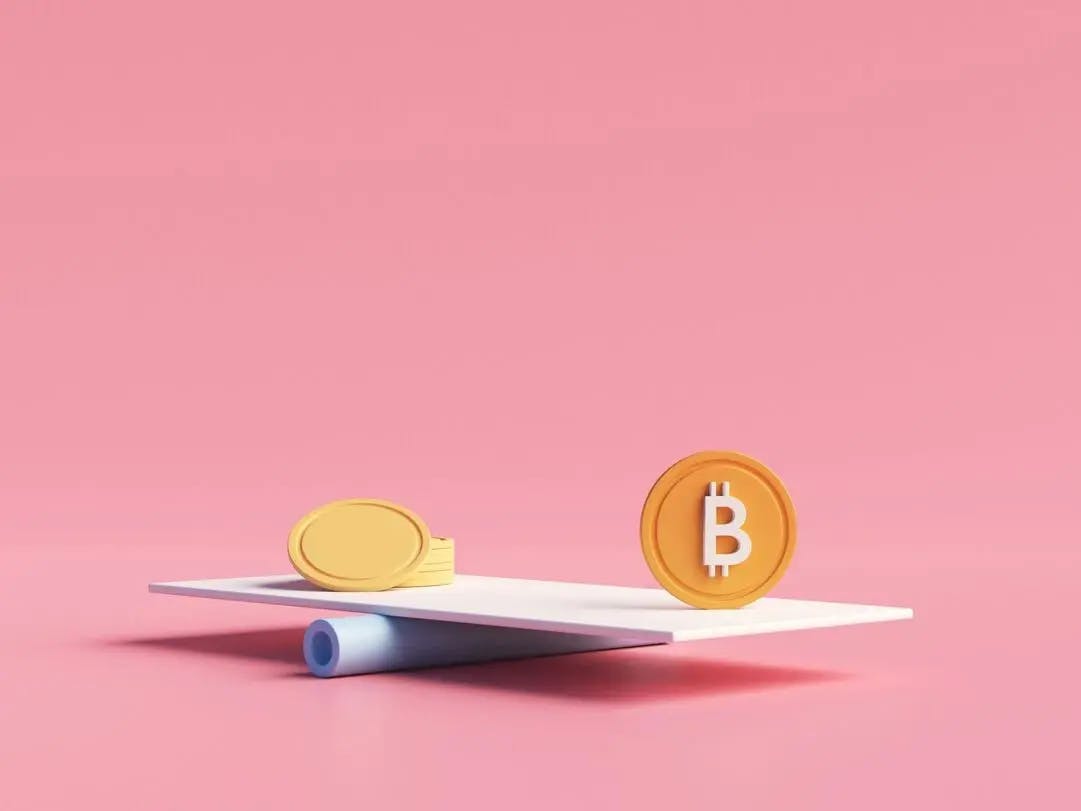 Plastic yellow gold coin and orange bitcoin token placed on scale against the pink background to compare the similarities and differences between gold and bitcoin