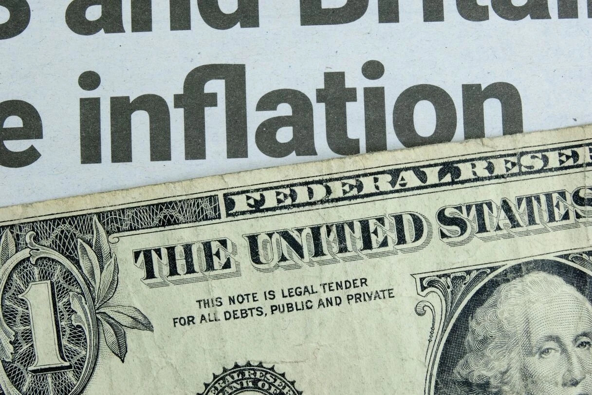 Ein US-Dollar-Schein liegt auf einer Zeitungsschlagzeile über die Inflation.