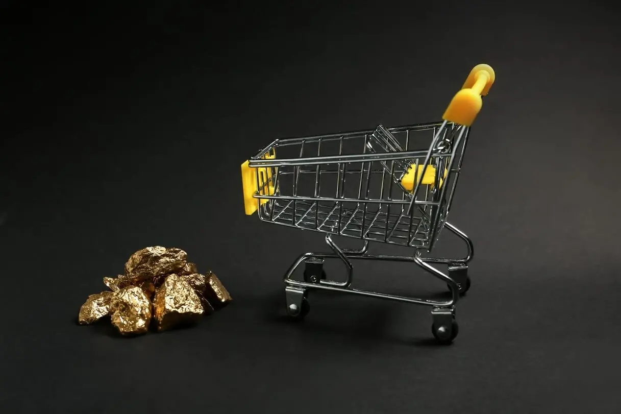 gold nuggets stacked next to a shopping cart