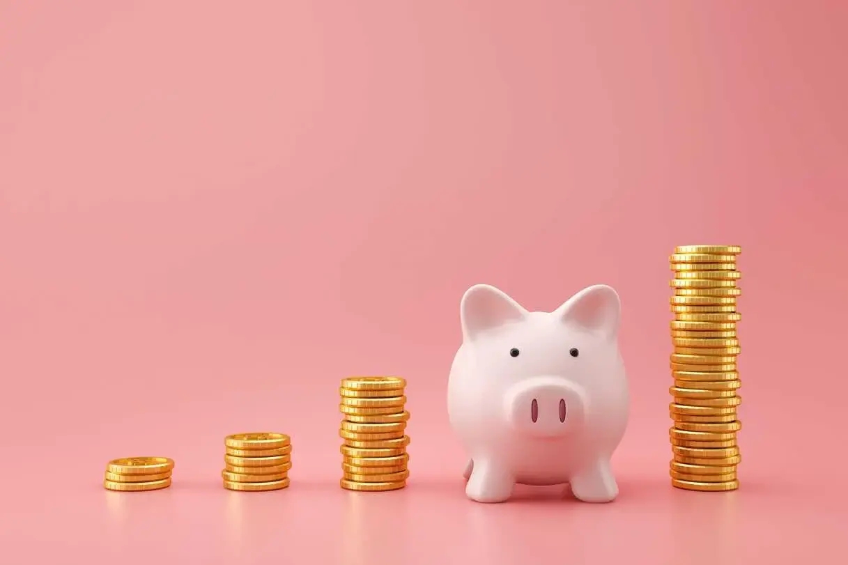 life savings in gold coins and a piggy bank on a pink background