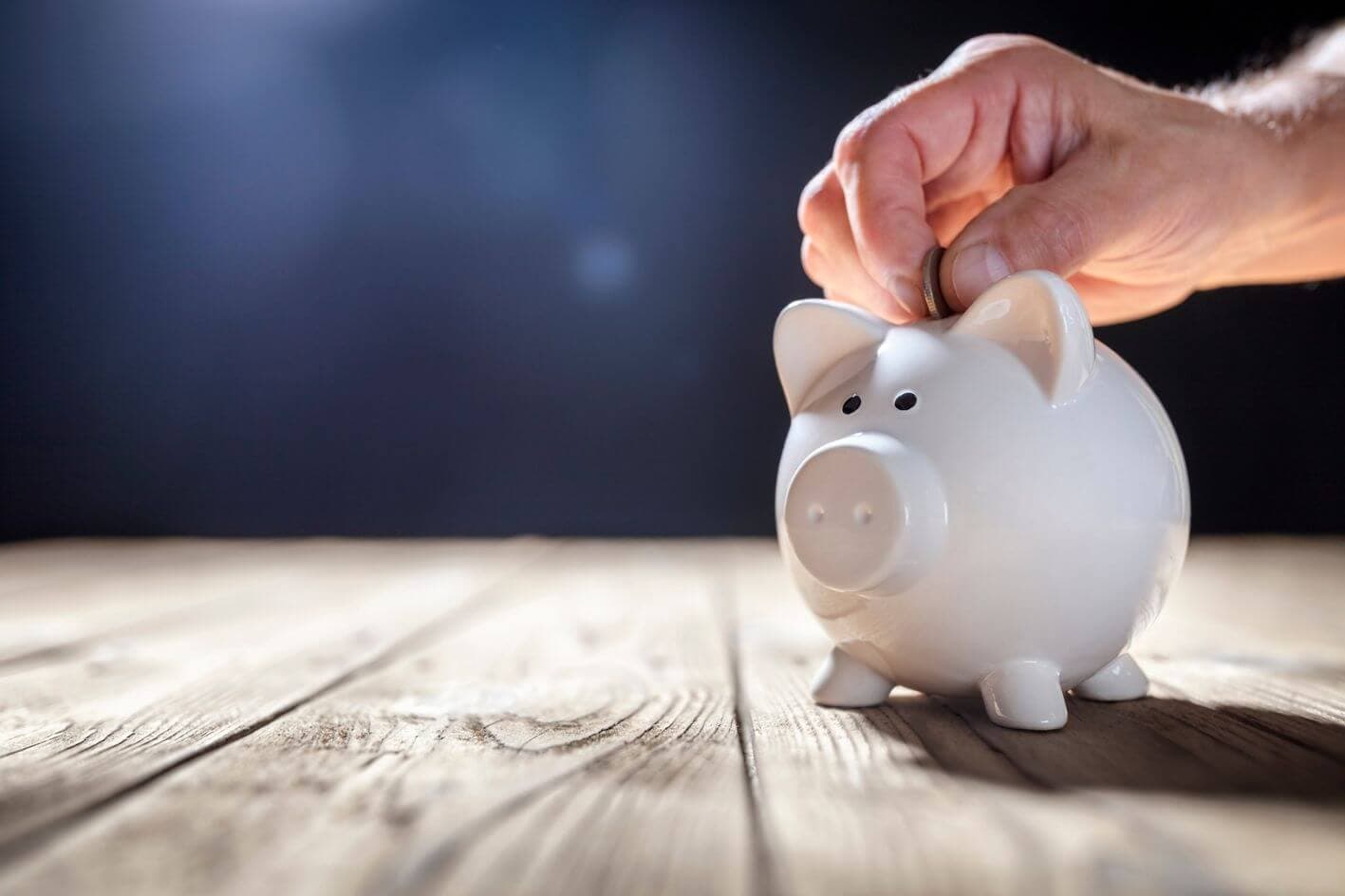 Un homme mettant une pièce dans une tirelire Un homme mettant une pièce dans une tirelire