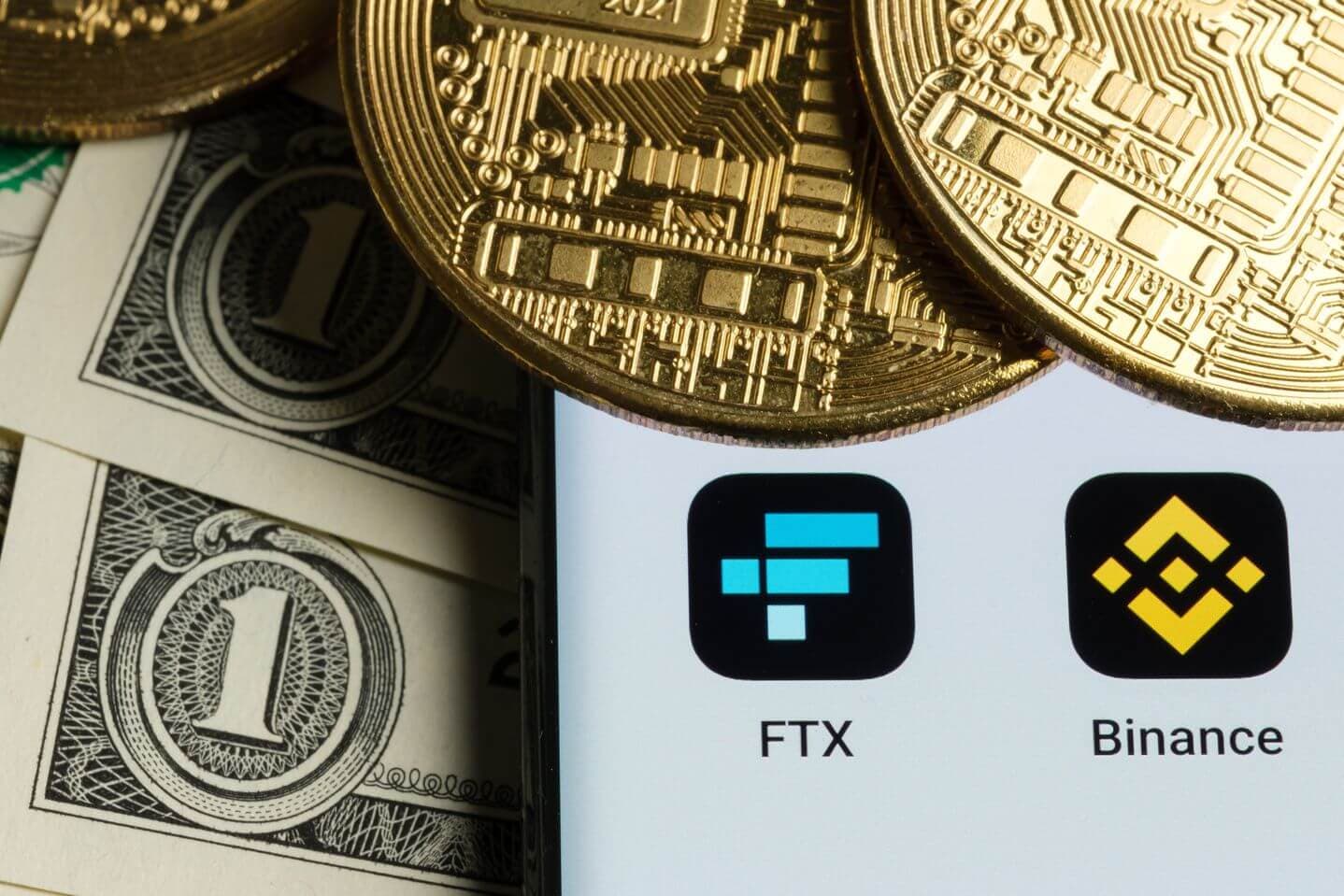 Ein Smartphone mit den Binance- und FTX-Apps auf Dollarscheinen und goldenen Bitcoin-Münzen Ein Smartphone mit den Binance- und FTX-Apps auf Dollarscheinen und goldenen Bitcoin-Münzen