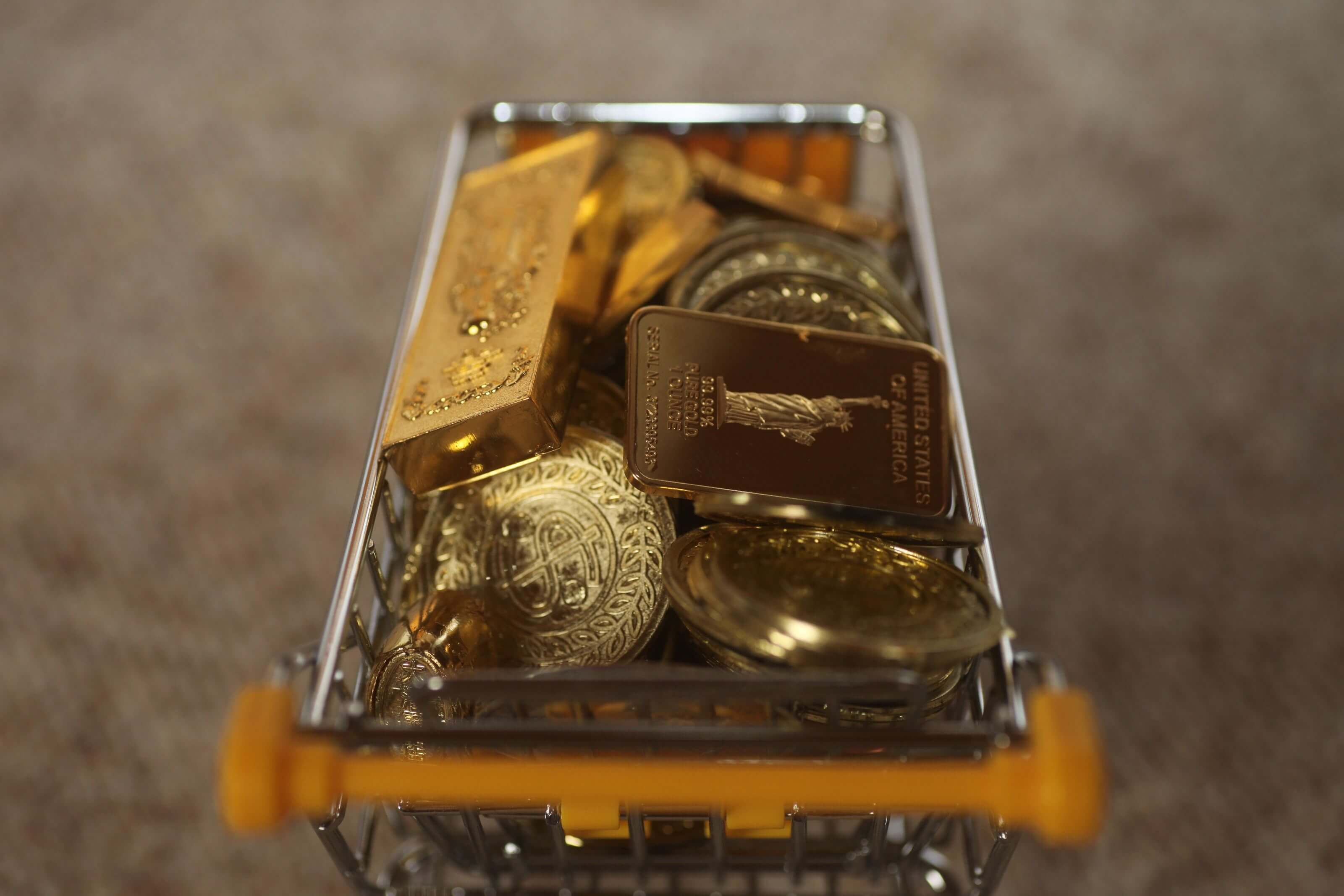 Wo kann man physisches Gold kaufen? Ein Einkaufswagen voller physischer Goldmünzen und -barren zum Kauf