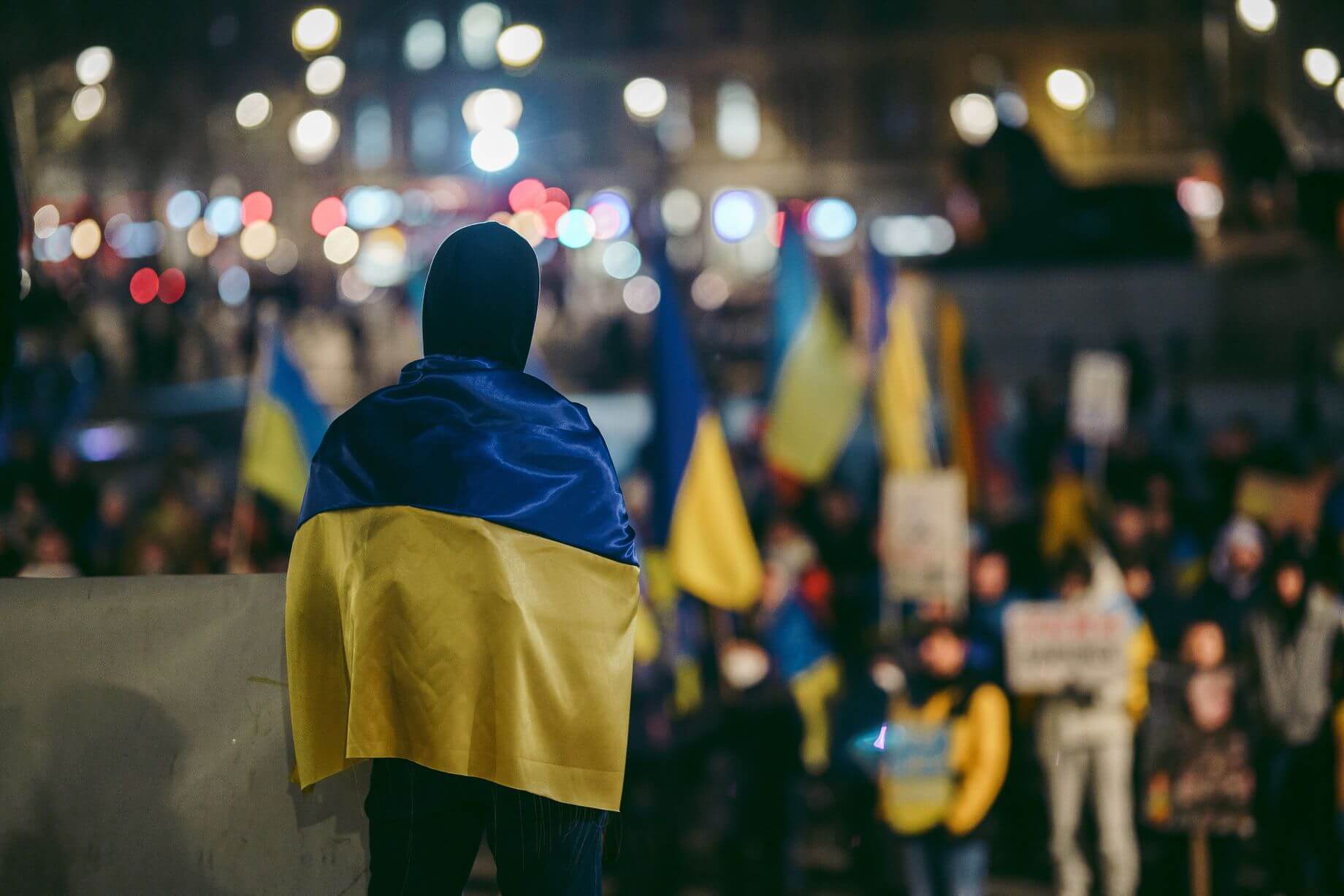 a man standing wrapped in a Ukrainian flag amid Russia’s ongoing military operation a man standing wrapped in a Ukrainian flag amid Russia’s ongoing military operation
