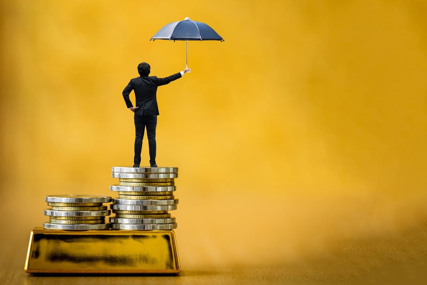 L’oro come protezione per eccellenza contro l’inflazione rappresentato con l’immagine di un uomo in giacca e cravatta in piedi su una pila di monete. L’oro come protezione per eccellenza contro l’inflazione rappresentato con l’immagine di un uomo in giacca e cravatta in piedi su una pila di monete.