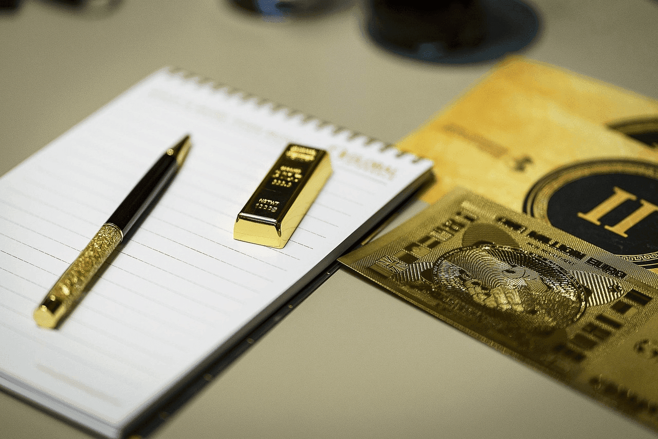 Un stylo en or posé à côté d'un petit lingot d'or Un stylo en or posé à côté d'un petit lingot d'or