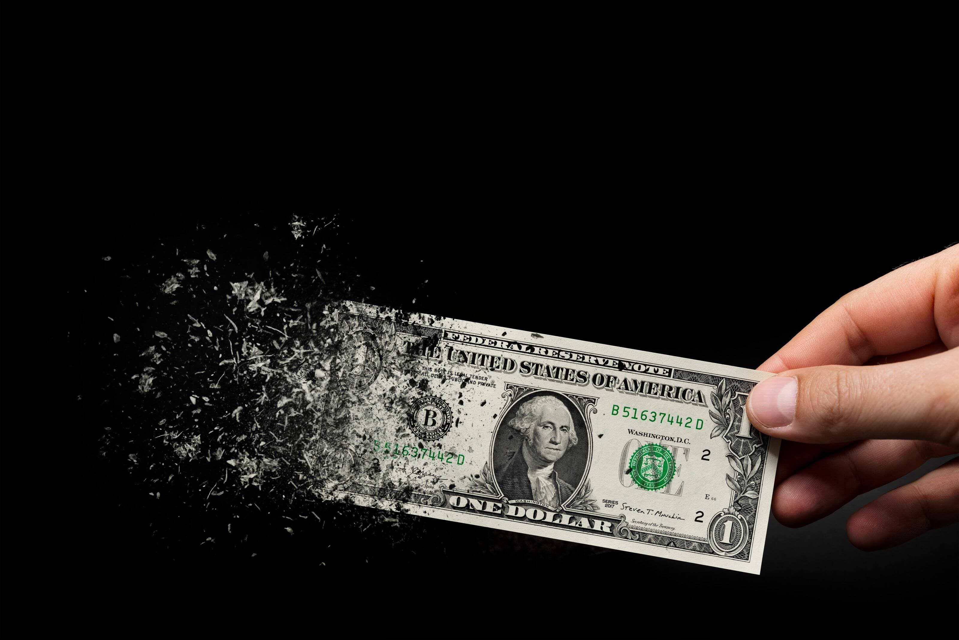 Wochenrückblick: Anleger setzen gegen den US-Dollar, Gold legt zu Eine Hand, die einen sich auflösenden Dollarschein hält