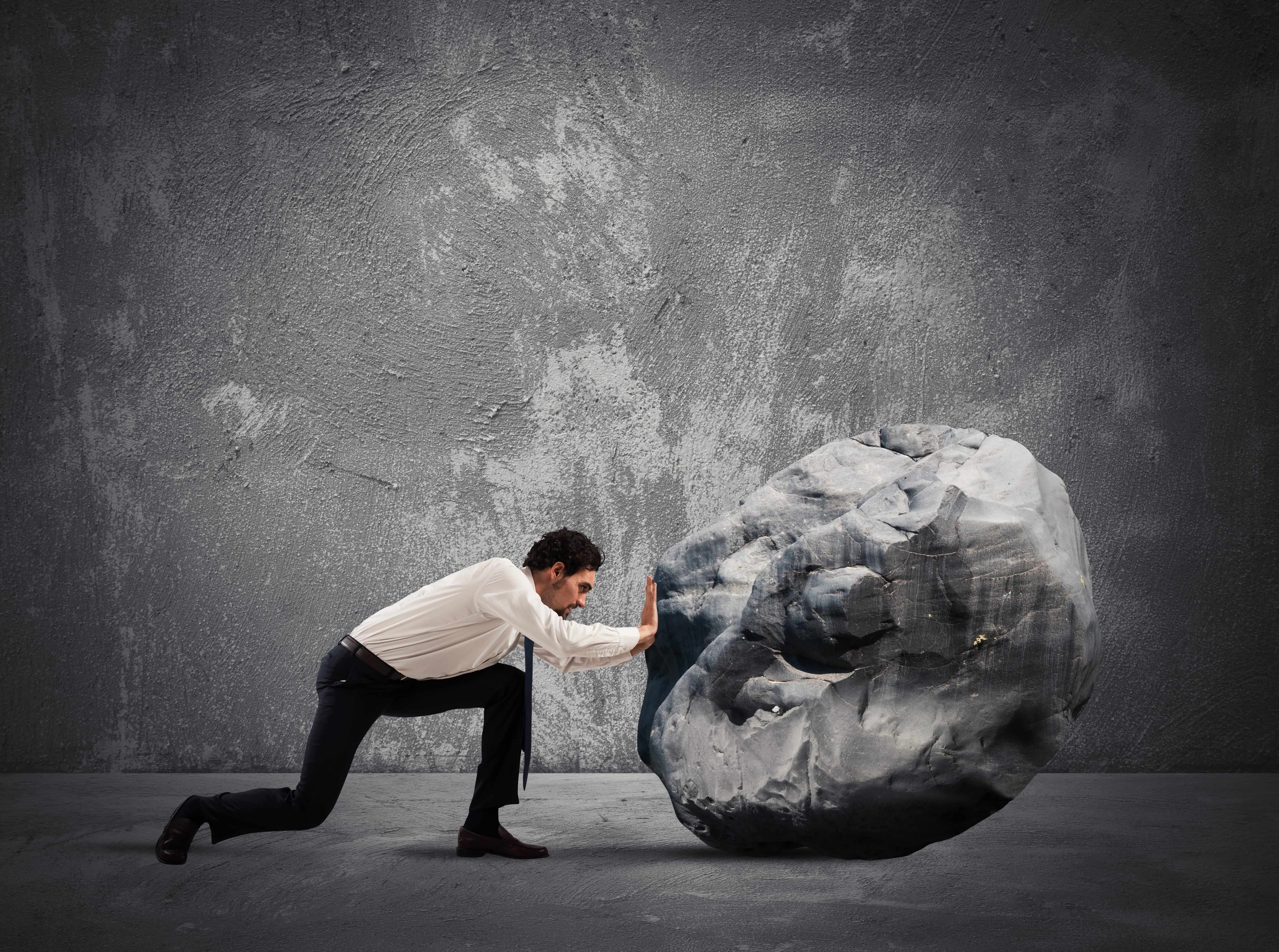 Businessman pushing a heavy boulder Businessman pushing a heavy boulder