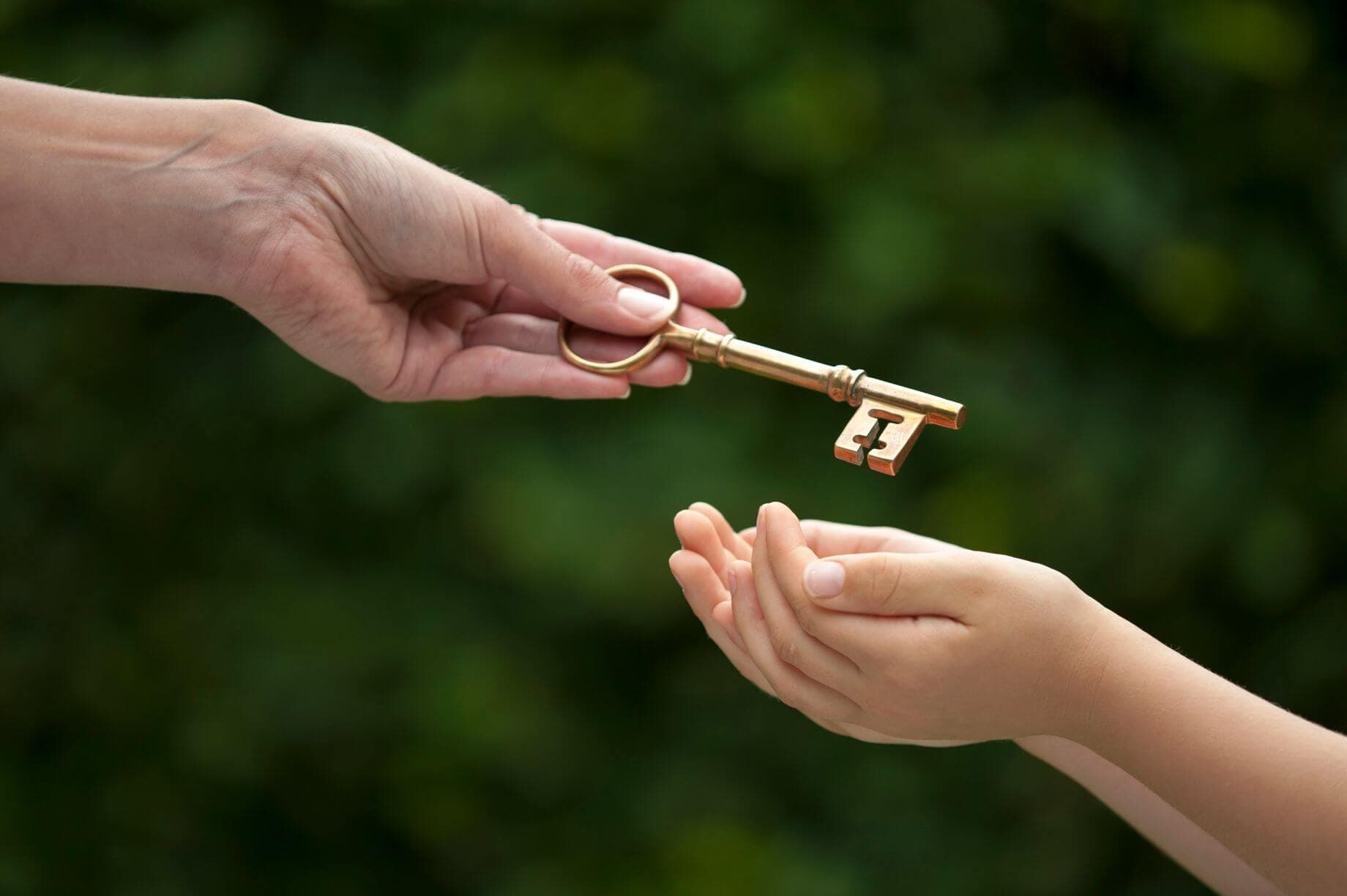 3 modi in cui il risparmio in oro può avvantaggiare figli e famiglia I genitori che iniziano a risparmiare il prima possibile per il futuro dei propri figli per offrire loro una rete di salvataggio rappresentati con la fotografia di un adulto che passa una chiave dorata a un bambino.