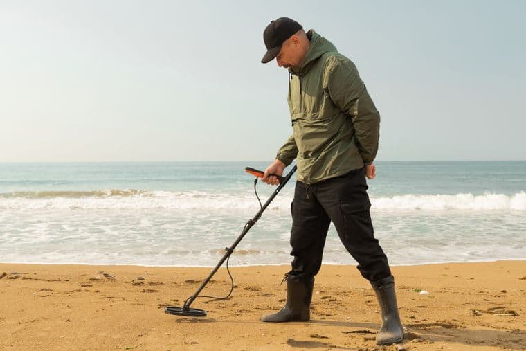 Un homme utilisant un détécteur de métaux sur une plage Un homme utilisant un détécteur de métaux sur une plage